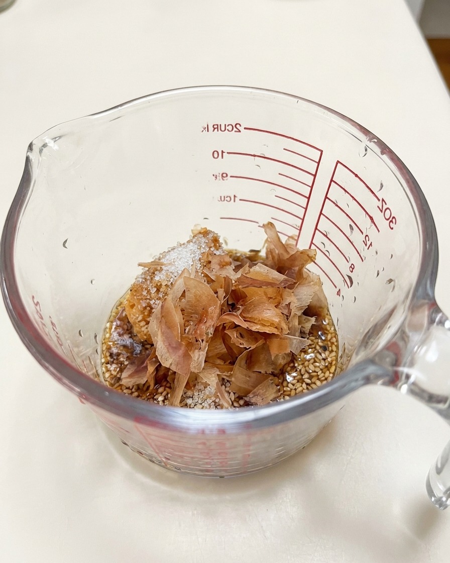 Fiocchi di bonito stratificati sopra la pasta di miso e i semi di sesamo allinterno di un misurino.