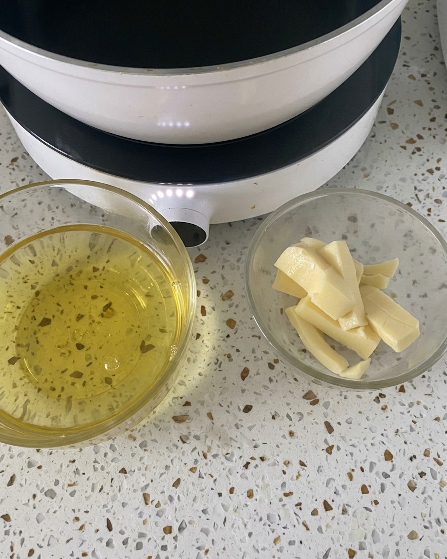 Due piccole ciotole di vetro contenenti uova sgusciate e fette di mozzarella sul bancone bianco vicino a un fornello.