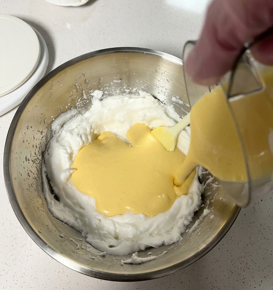 La pastella gialla e liscia viene versata nella ciotola con gli albumi montati a neve.