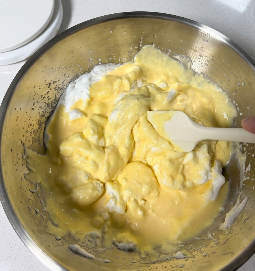 Movimento delicato per amalgamare limpasto giallo pallido e gli albumi montati usando una spatola in silicone.