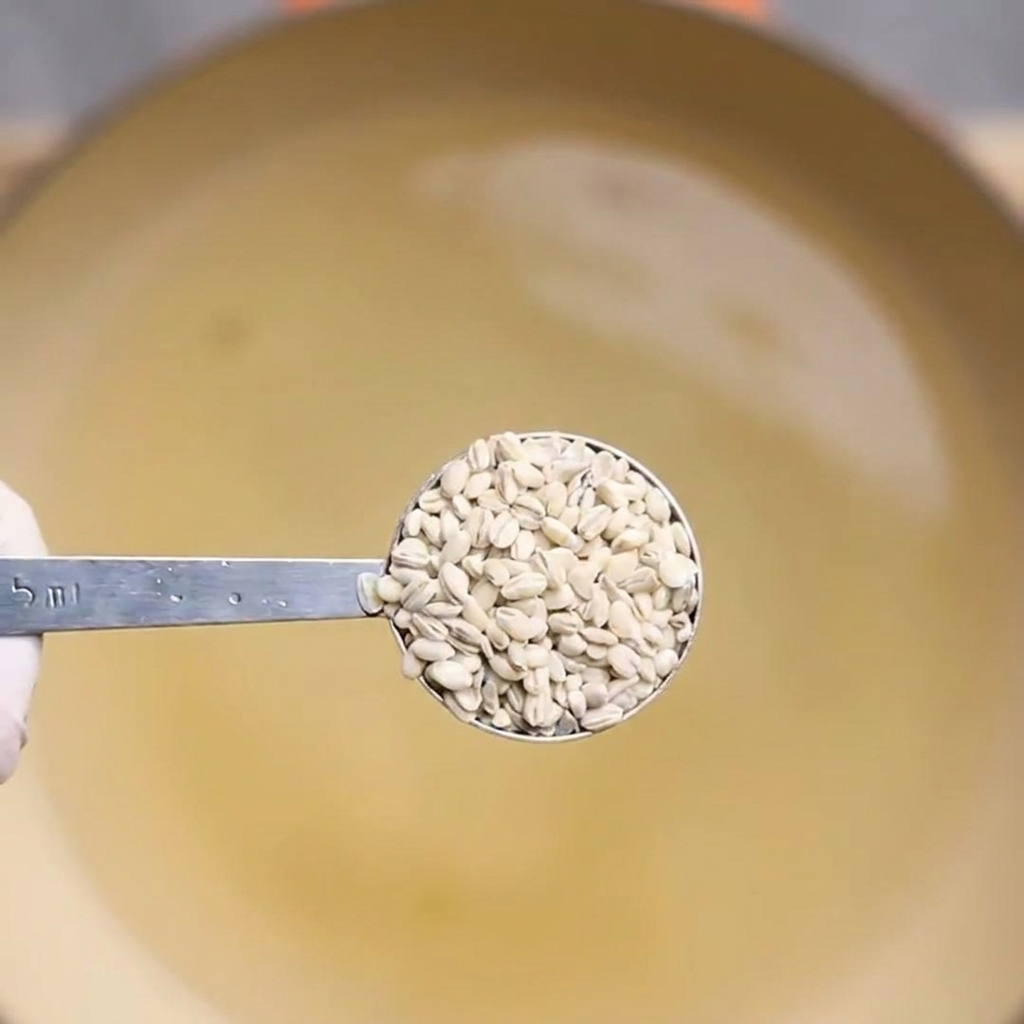 Un cucchiaio che solleva lorzo cotto da una pentola dacqua bollente.