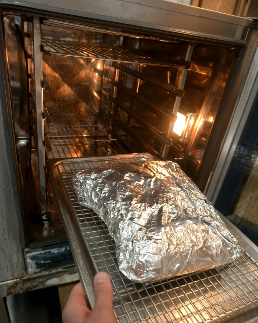 Il pacchetto di alluminio con le costine viene posizionato su una griglia allinterno del forno caldo.