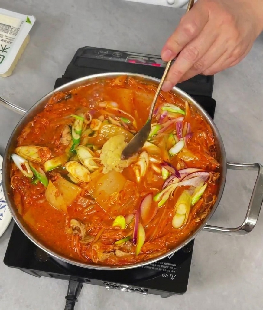 Aggiungere un cucchiaio di aglio fresco tritato in una padella fumante di stufato di kimchi.