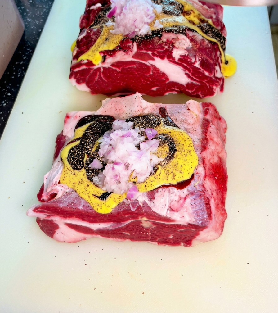 Manzo crudo ricoperto di salse e cipolle rosse tritate su un tagliere.