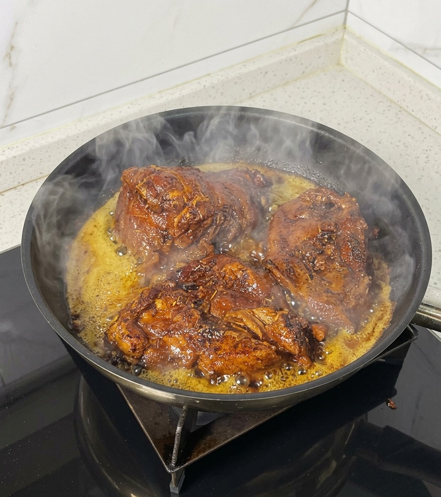 Tre grossi pezzi di maiale che sfrigolano in una padella nera con vapore e olio bollente.
