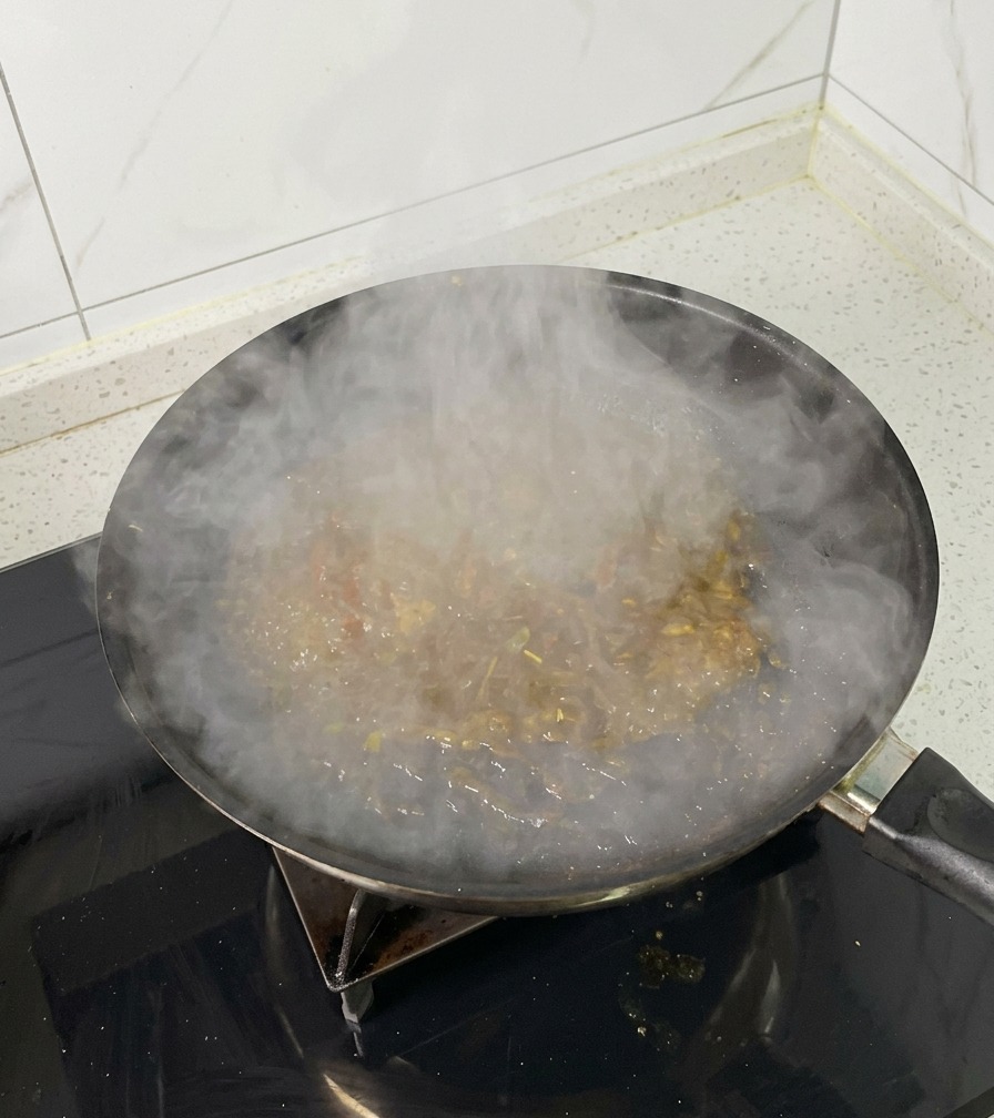 Una padella sul fuoco con il liquido di brasatura che bolle e si riduce, rilasciando molto vapore.