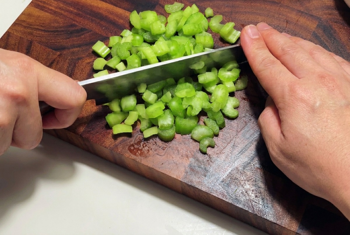 Una cipolla bianca sminuzzata finemente su un tagliere di legno.