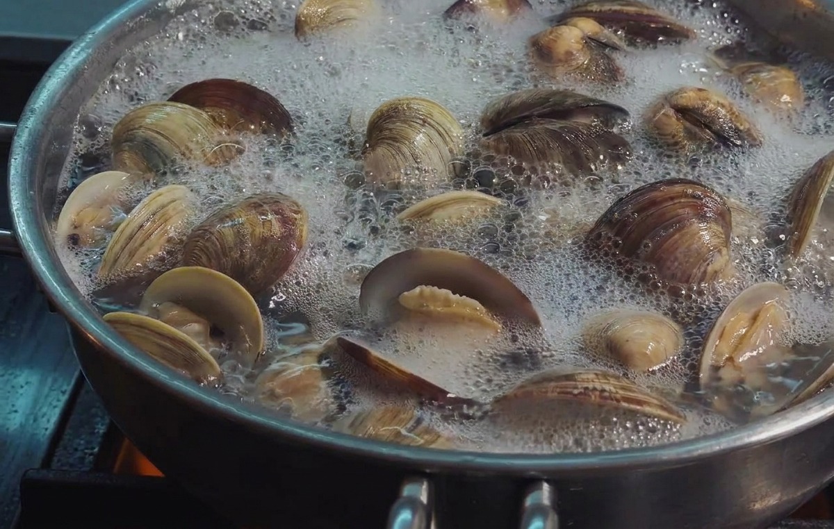 Vongole fresche che sobbollono in padella con la maggior parte dei gusci aperti per mostrare il frutto.