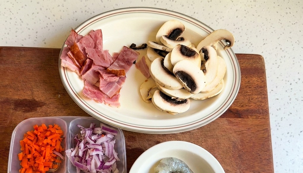Un piatto bianco con funghi champignon affettati e pezzi di pancetta tritata.