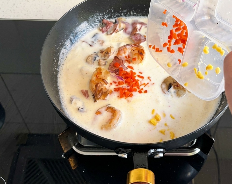Carote a dadini e mais versati da un contenitore nella zuppa cremosa.