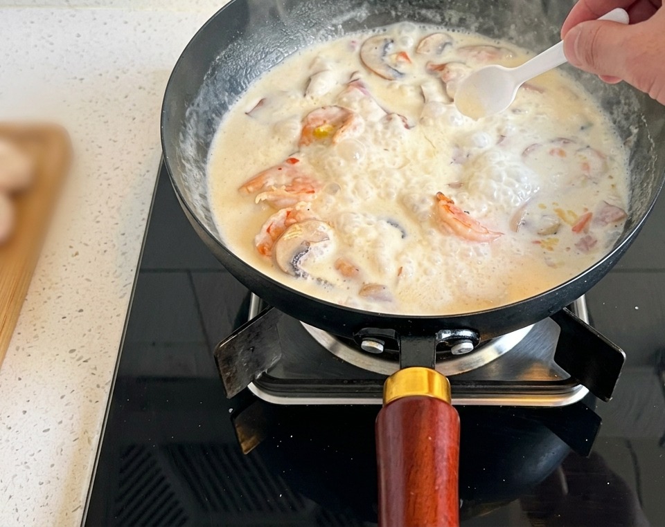 Un cucchiaino bianco che aggiunge un pizzico di sale alla vellutata di funghi.