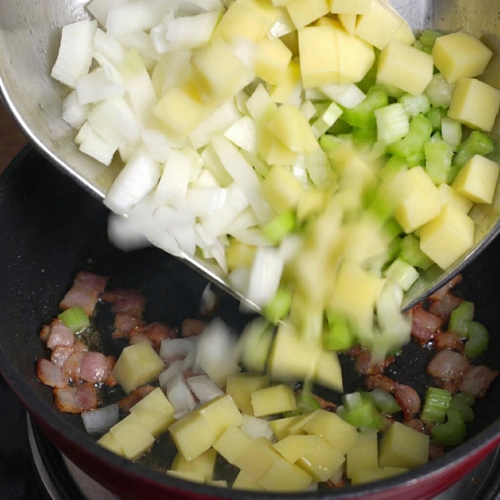 Patate, sedano e cipolle versati da una ciotola di metallo in una pentola con bacon croccante.