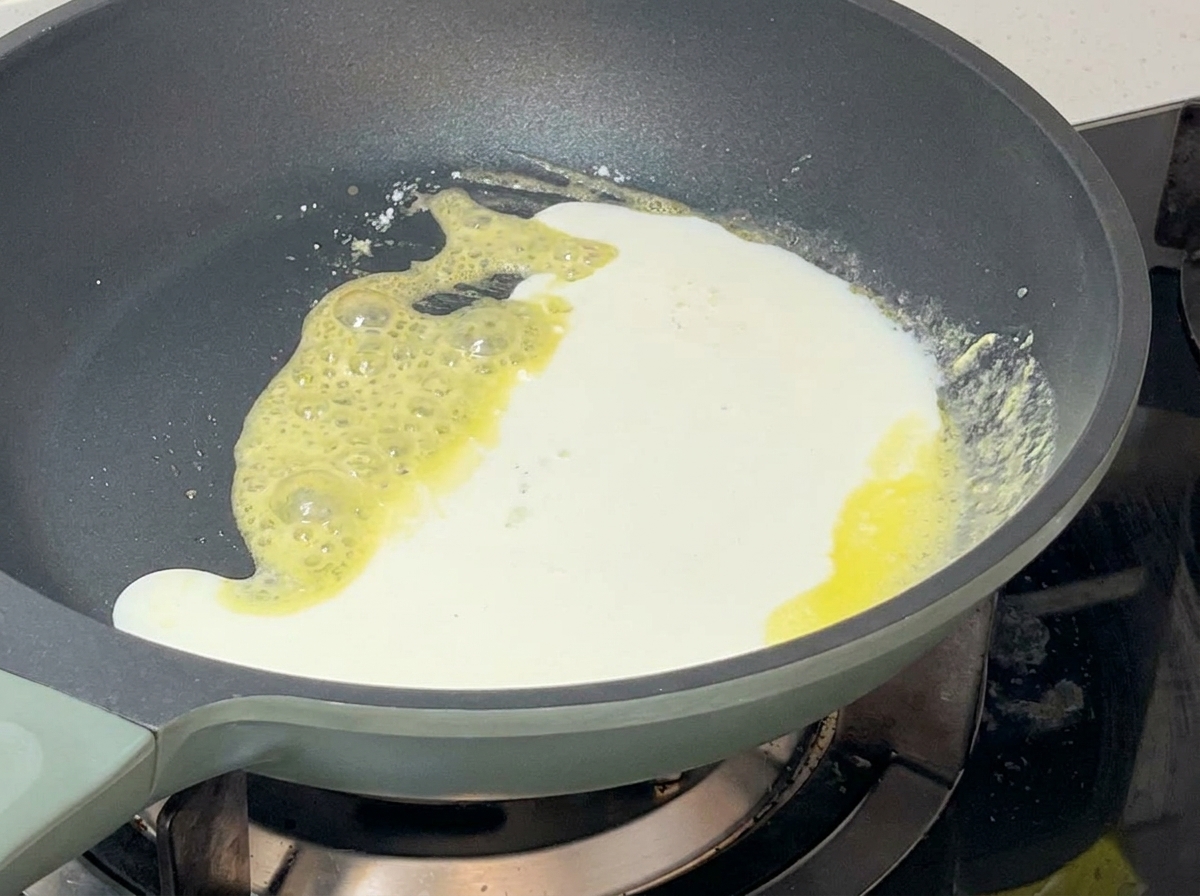 Miscela di latte e panna versata in una padella con il roux giallo, creando una salsa bianca densa.