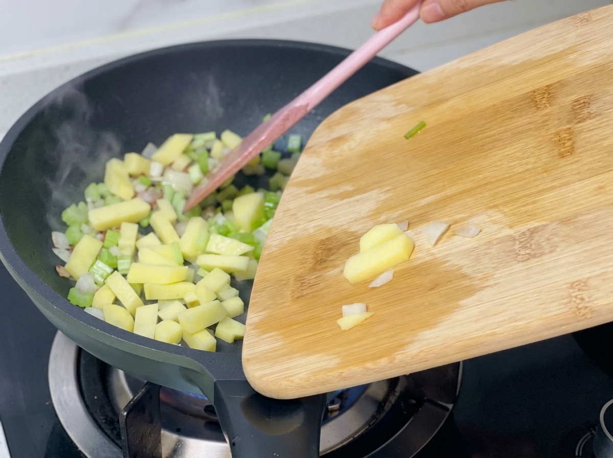 Dadini di patate aggiunti alla padella che contiene già sedano, cipolle e pancetta soffritti.