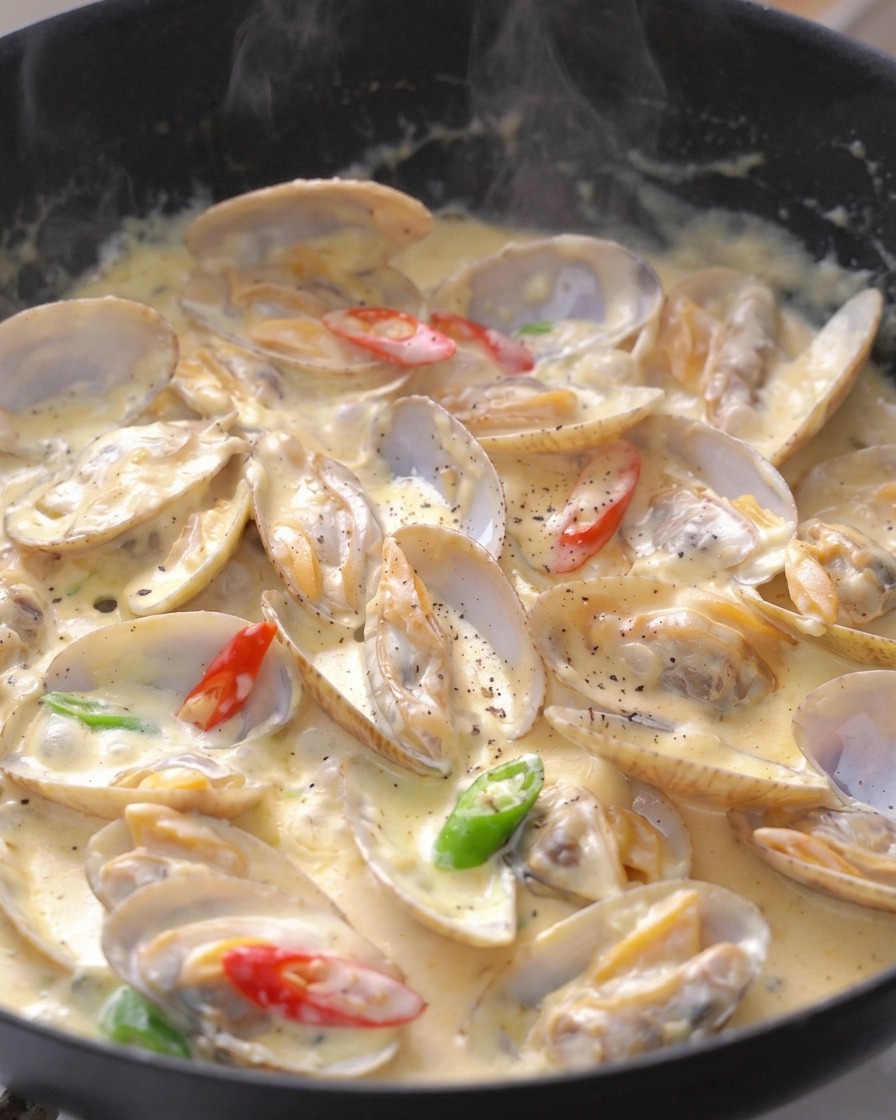 Vongole cremose guarnite con fettine di peperoncino rosso e verde e pepe nero macinato.