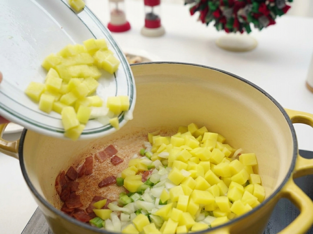Patate, sedano e cipolle a cubetti versati da un piatto bianco in una pentola con la pancetta.