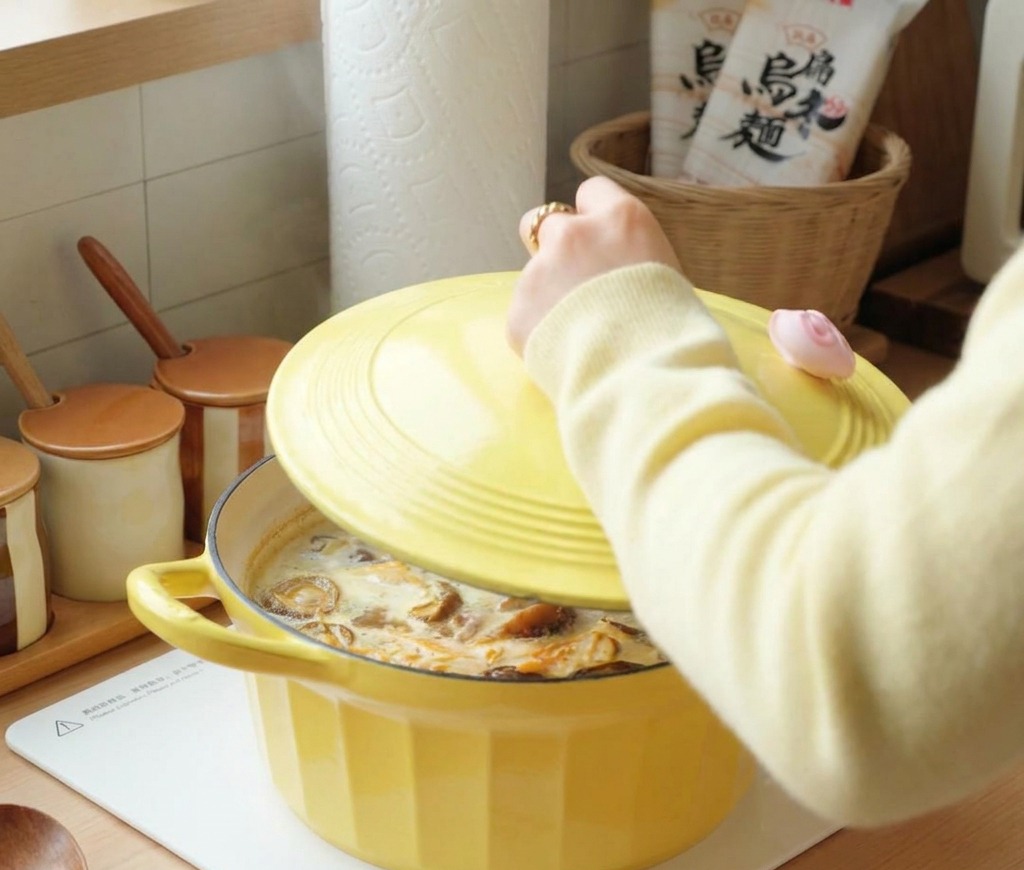 Una persona che mette un coperchio giallo su una pentola di zuppa di pollo e funghi che bolle.