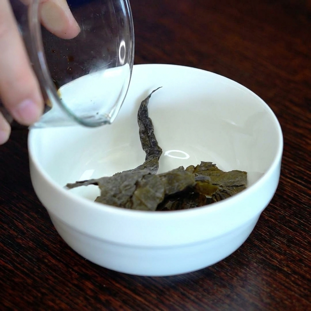 Salsa di soia scura versata su un pezzo di kombu essiccato in una piccola ciotola di ceramica bianca.