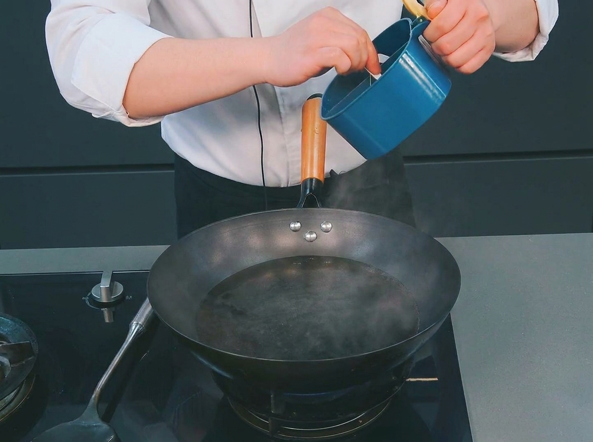 Uno chef che aggiunge un cucchiaio di sale in un wok con acqua bollente fumante.