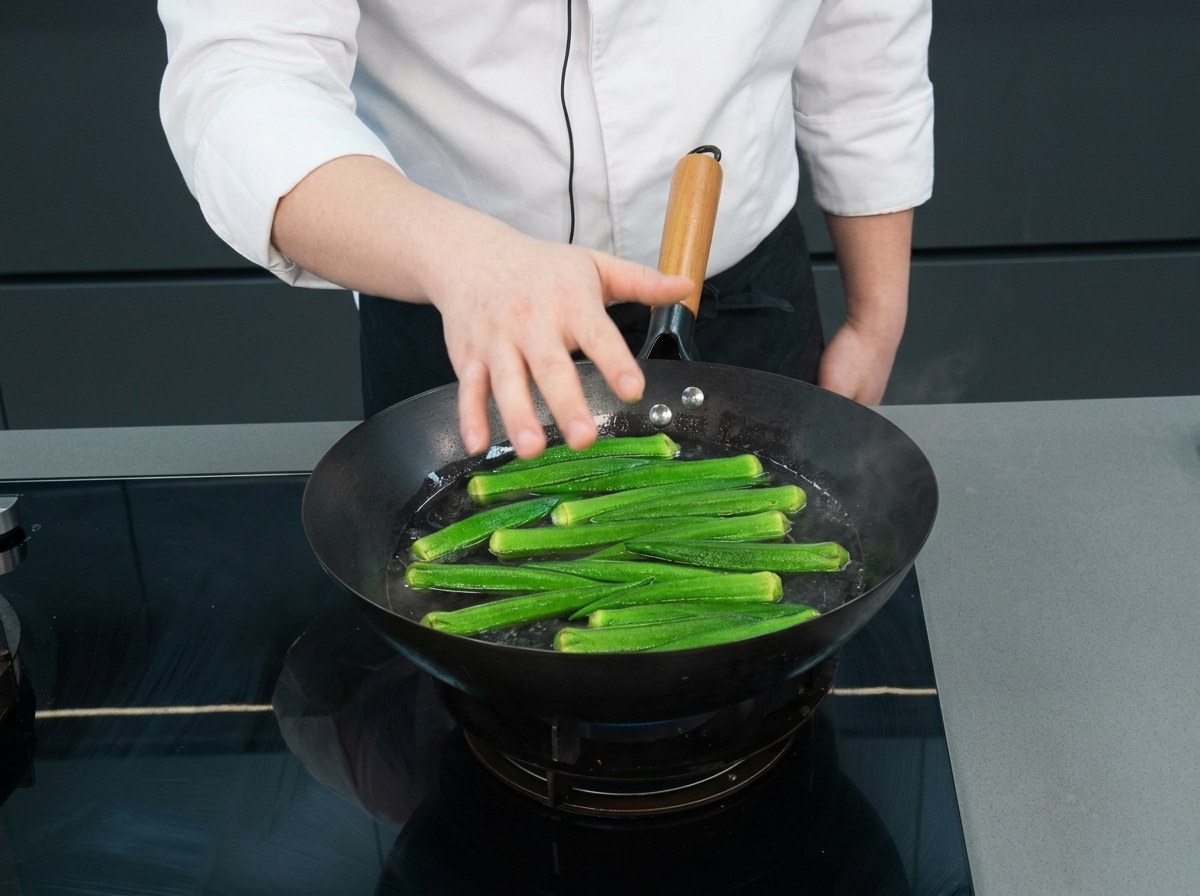 Okra verde intera che galleggia in un wok di acqua bollente mentre lo chef la controlla.