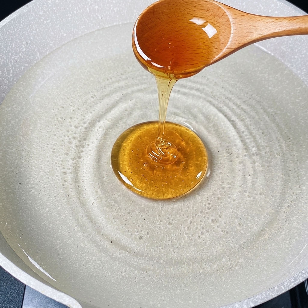 Un cucchiaio di legno che versa un filo di olio dorato in una pentola dacqua calda.