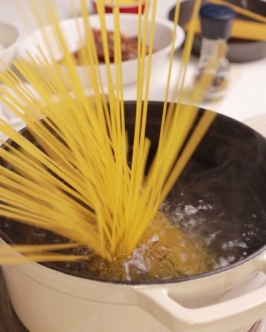 Spaghetti secchi calati in una pentola di acqua bollente.