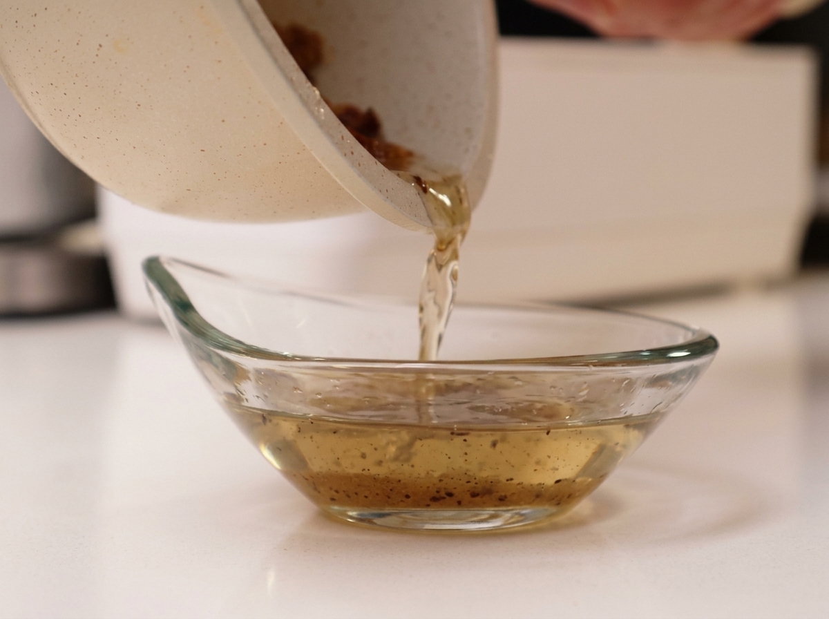 Grasso fuso del guanciale versato dalla padella in una ciotolina di vetro.