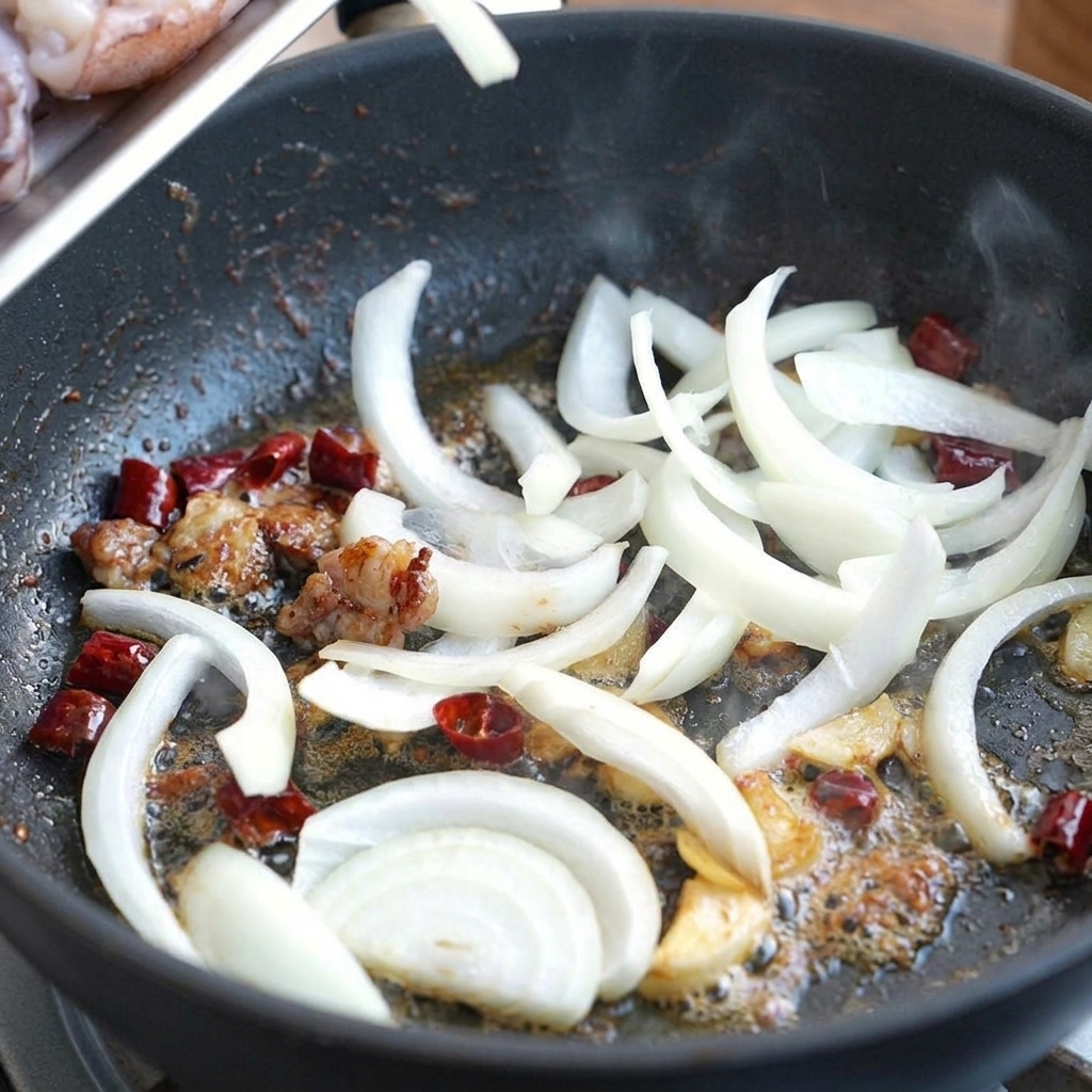 Cipolle bianche affettate che saltano in padella con lolio aromatizzato, peperoncini e aglio.