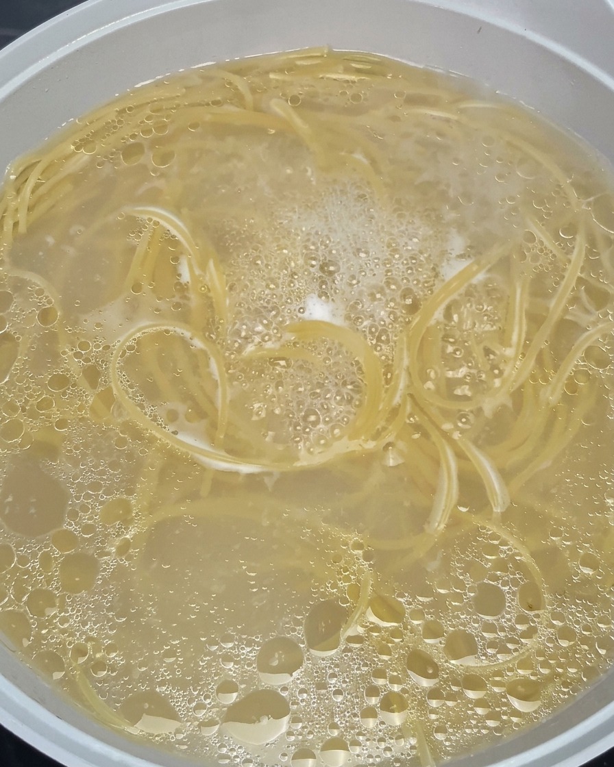 Spaghetti che si ammorbidiscono in una pentola di acqua bollente e spumeggiante.