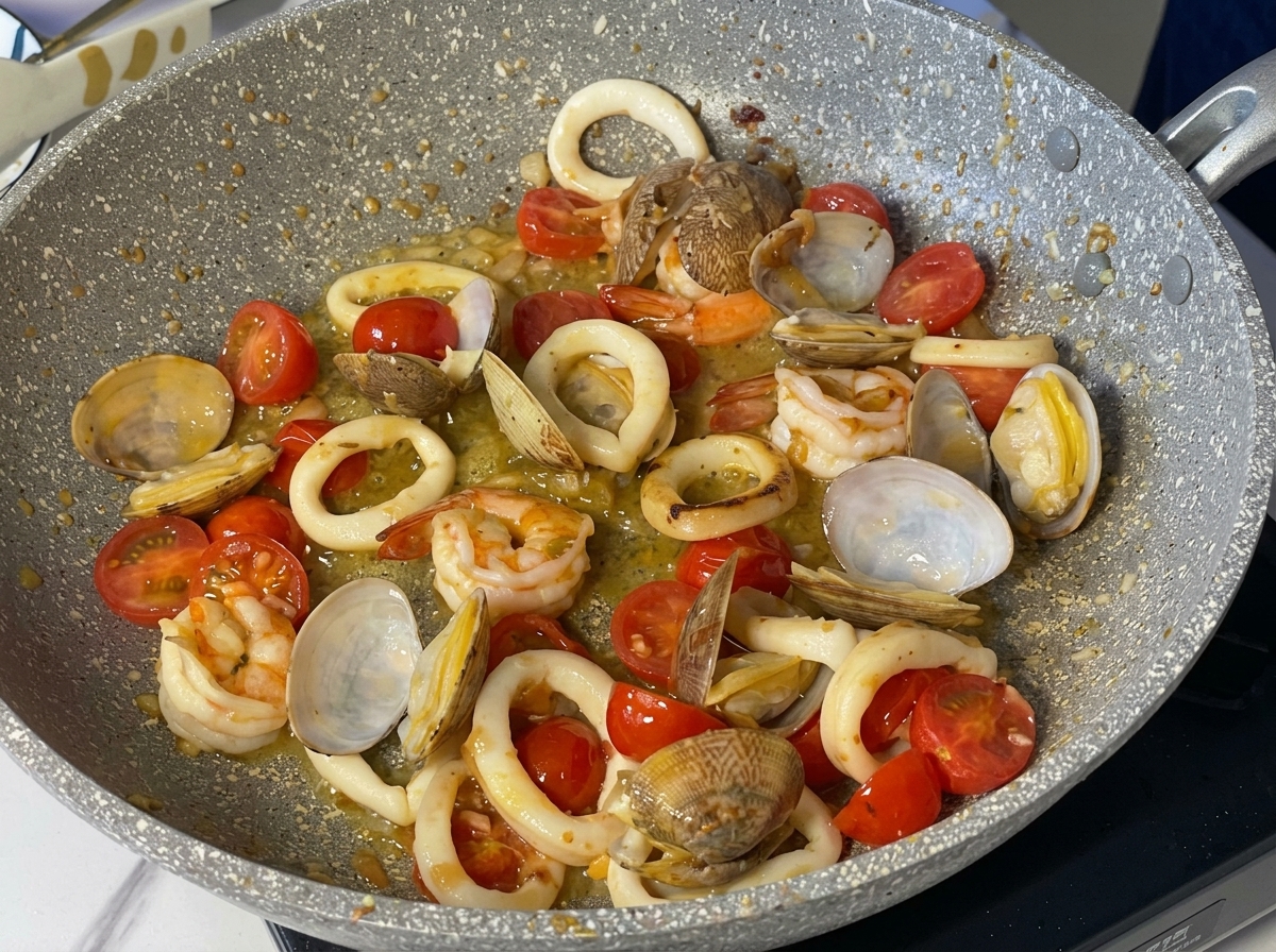 Gamberi, calamari, vongole e pomodorini che sobbollono in una salsa al burro e vino bianco.