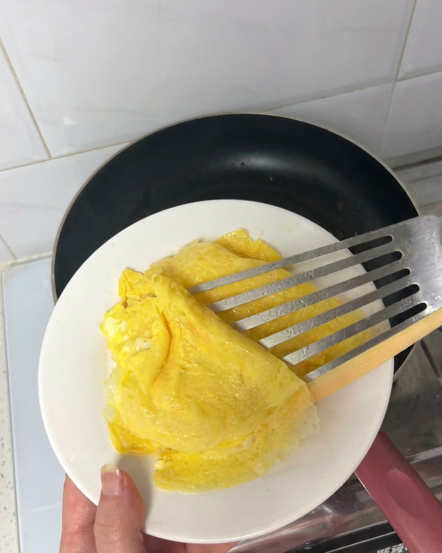 Strisce di bacon che friggono in una padella antiaderente calda rilasciando il grasso.