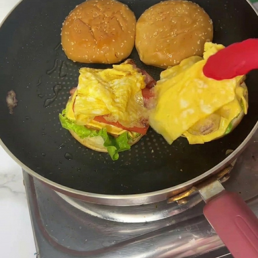 Un burger per colazione finito su un piatto con la parte superiore del panino al sesamo ben posizionata.