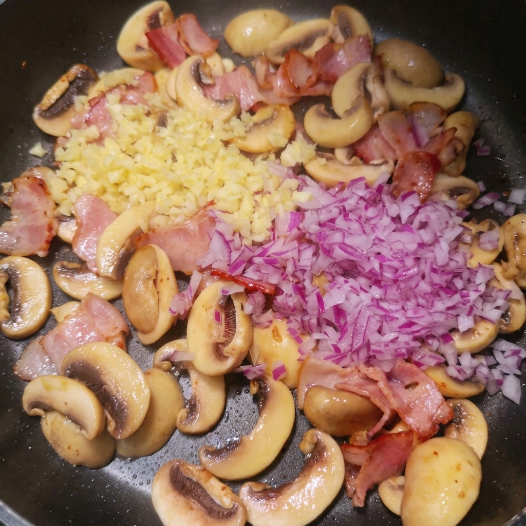 Cipolla e aglio tritati sopra la pancetta e i funghi in padella.