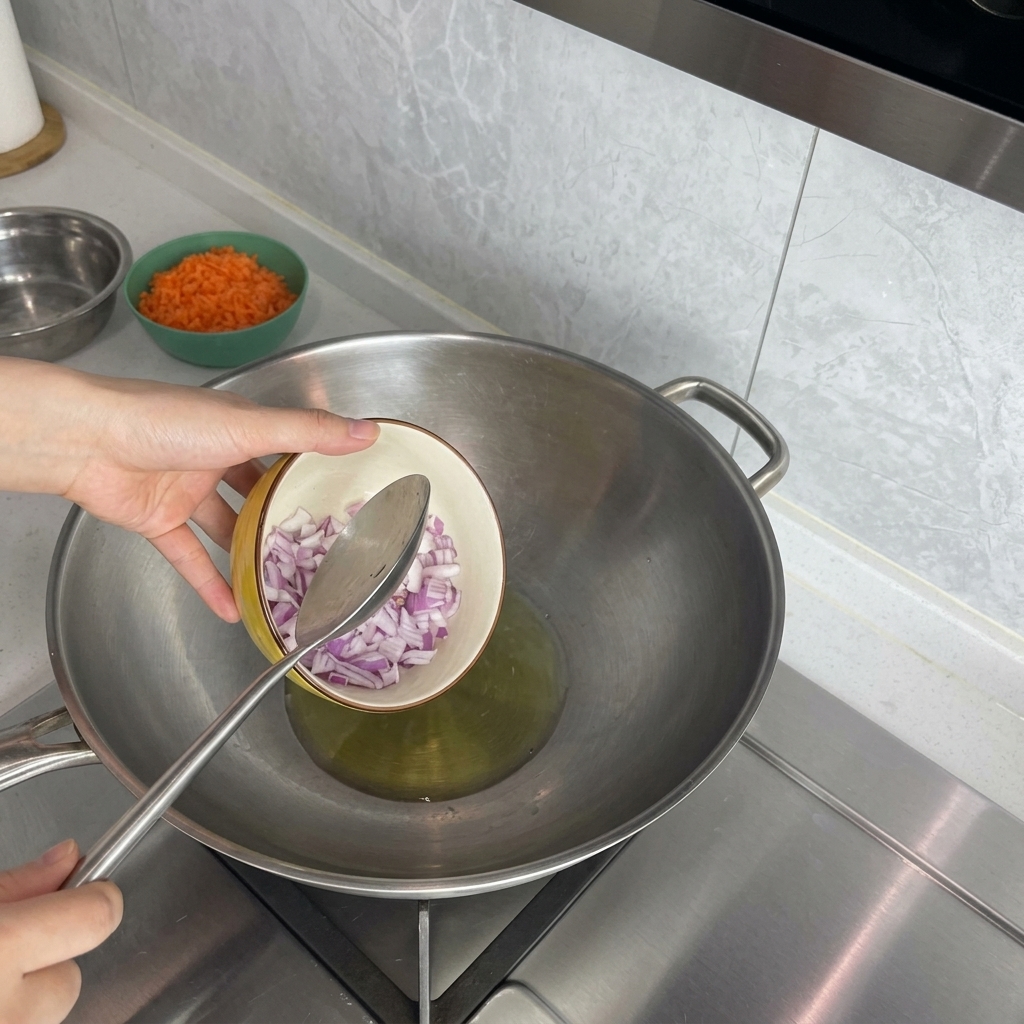 Una mano versa la cipolla rossa a dadini in un wok con olio caldo.