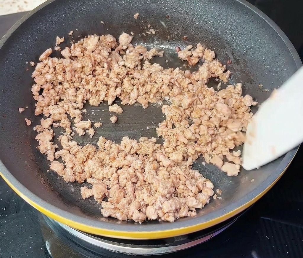 Manzo macinato mescolato in padella, appare perfettamente rosolato e sgranato.