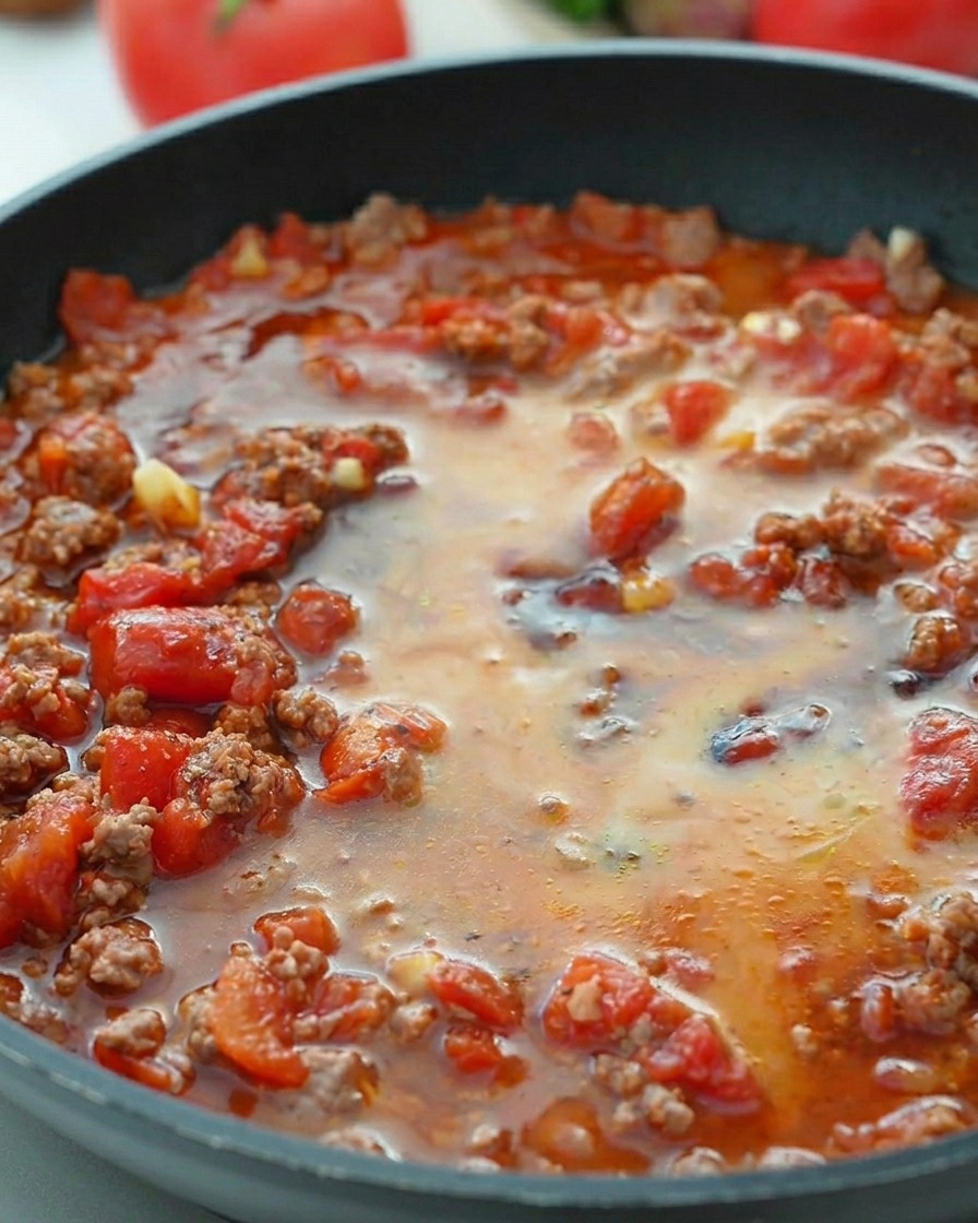 Acqua con amido versata nel ragù di pomodoro che bolle.