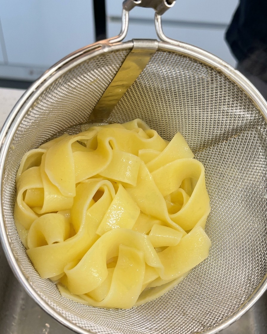 Pappardelle cotte in un colino dopo essere state sollevate dallacqua bollente.