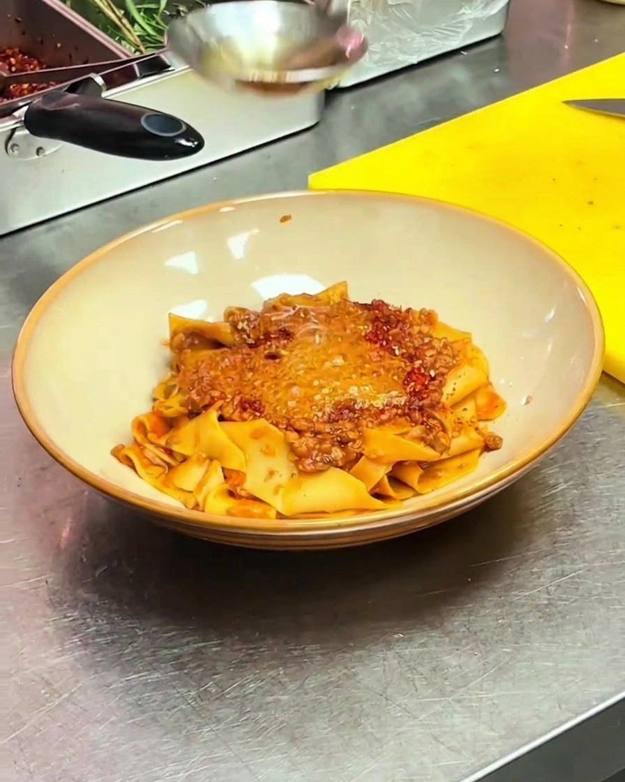 Un uovo in camicia viene adagiato delicatamente al centro della pasta coperta di olio piccante.