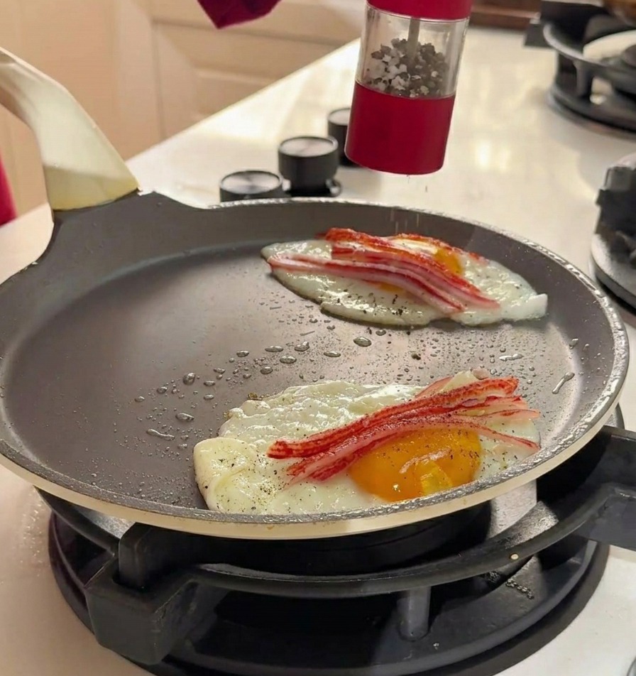 Macinatura di sale marino e pepe nero da un macinino rosso sopra le uova e il granchio in padella.