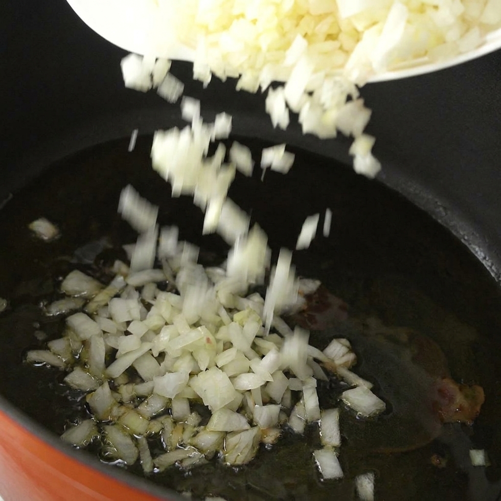 Cipolla bianca tritata finemente che cade in una pentola con olio caldo.