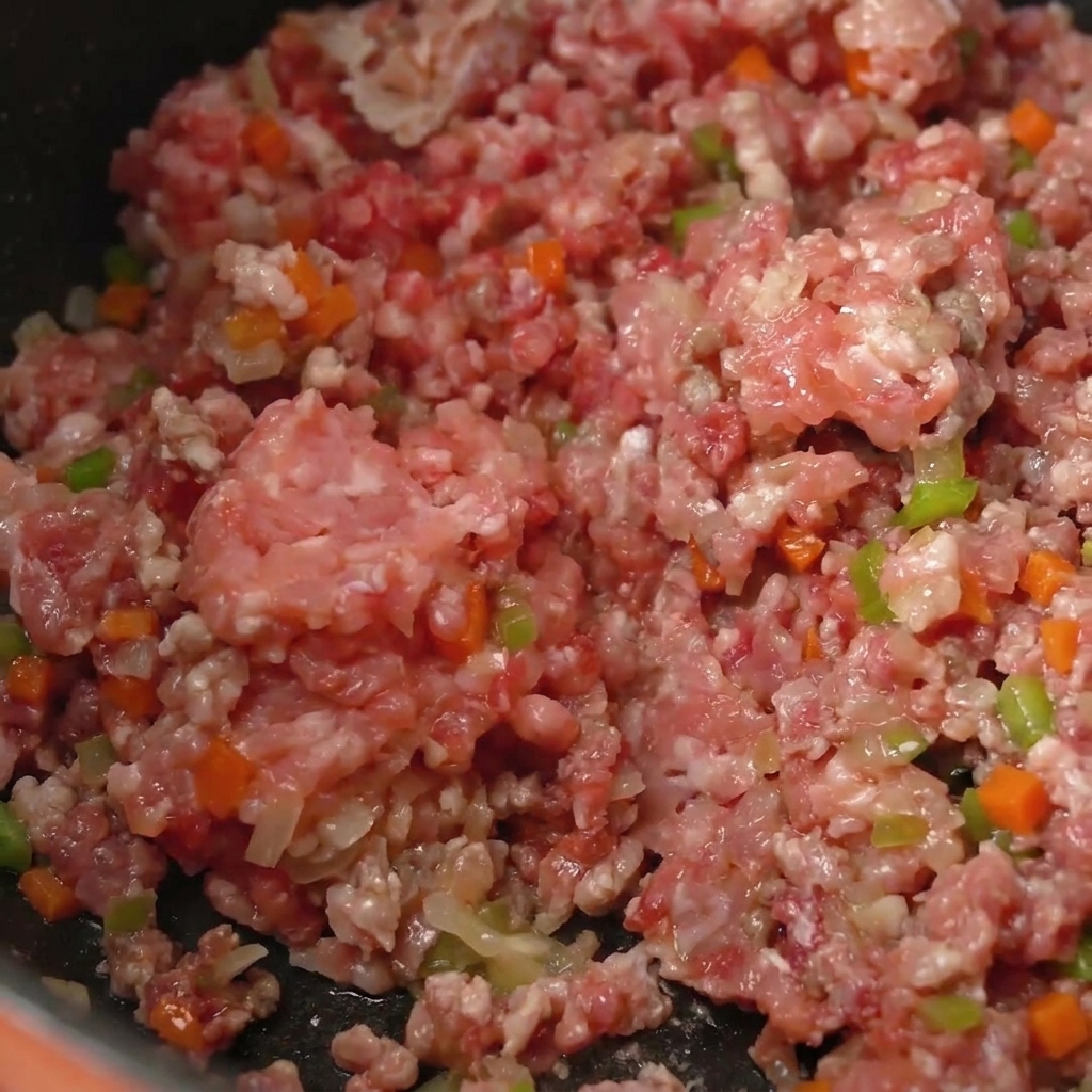 Primo piano della carne macinata che rosola uniformemente con le verdure.