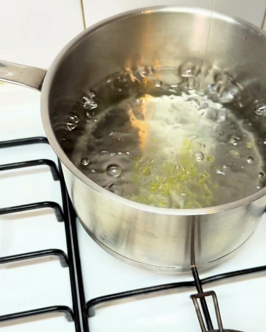 Paccheri secchi versati in una pentola di acqua bollente salata.