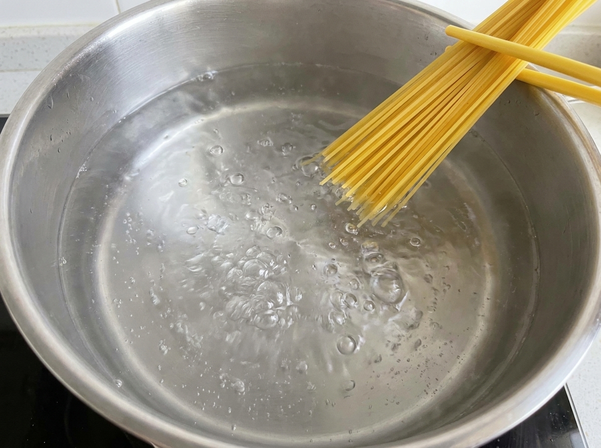 Spaghetti secchi immersi in una pentola di acqua che bolle vivacemente.