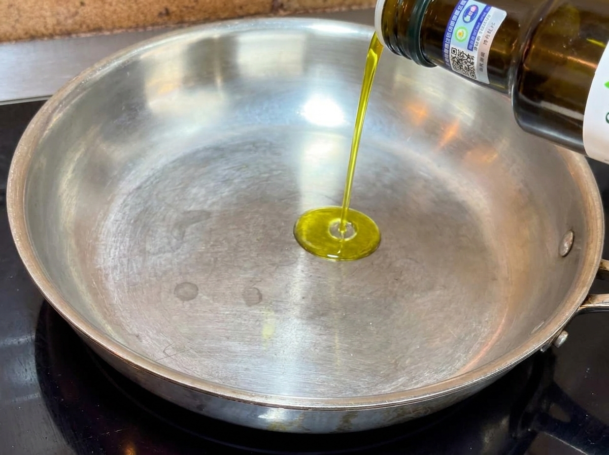 Olio extravergine doliva versato in una padella di metallo dal fondo piatto.