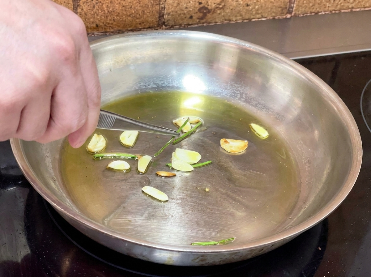 Pinze da cucina che rimuovono i gambi di prezzemolo fritti dalla padella con lolio allaglio.