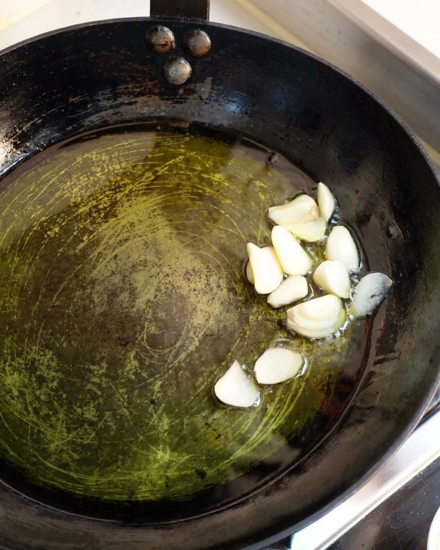 Fette spesse di aglio bianco che sfrigolano delicatamente nellolio doliva caldo.