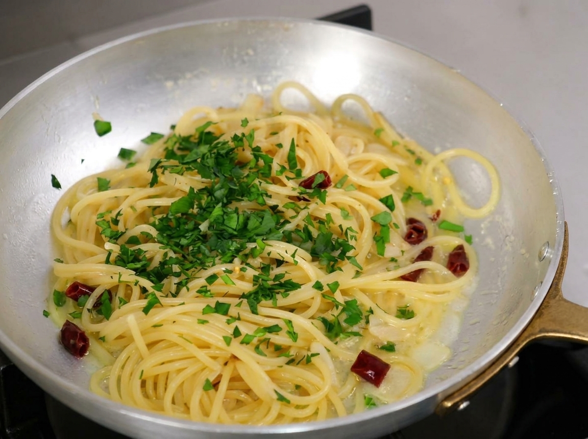 Prezzemolo fresco tritato cosparso generosamente sugli spaghetti in padella.