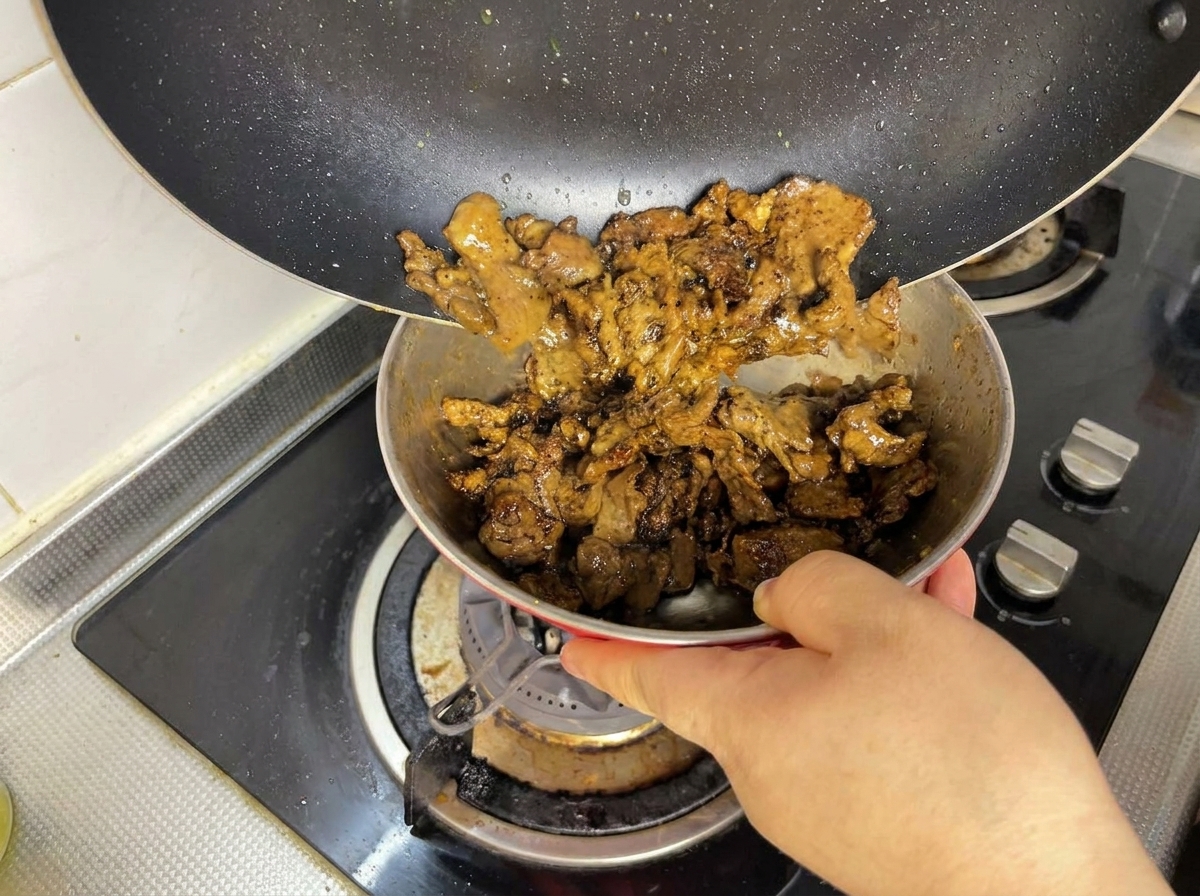 Pezzetti di manzo rosolati versati da una padella in una ciotolina.