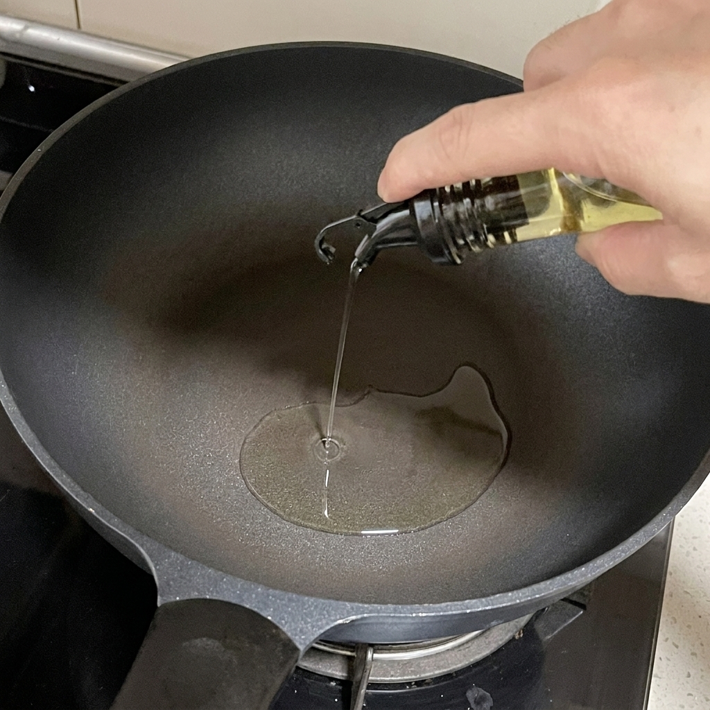 Olio doliva versato da un contenitore di vetro in una padella scura sul fornello.
