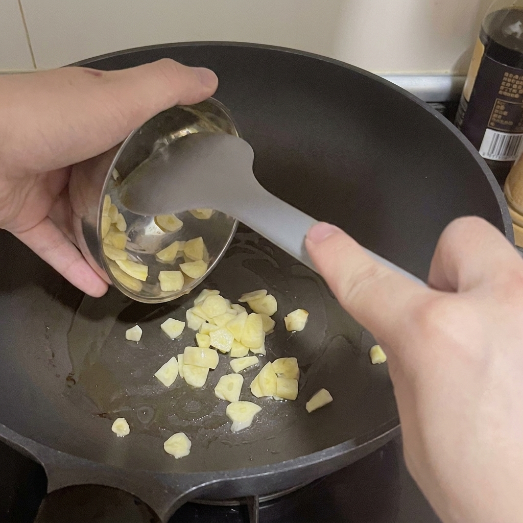 Aglio affettato che viene versato da una ciotolina in una padella calda con olio.